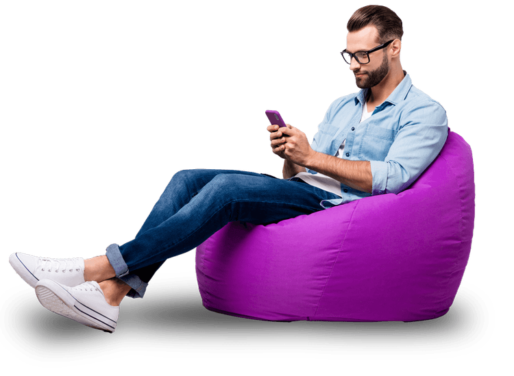 Imagem de um homem sentado em uma almofada enquanto navega em seu celular